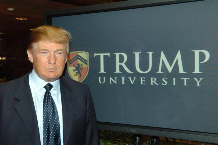 Donald Trump in front of Trump University logo